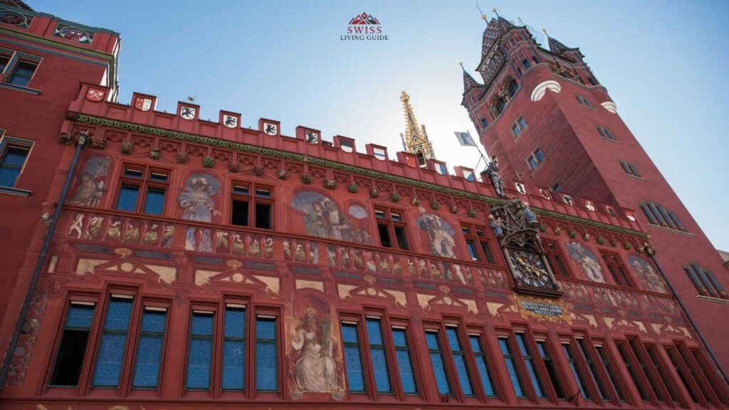 Basel Rathaus in Marktplatz with its vibrant red facade and lively market scene during daytime