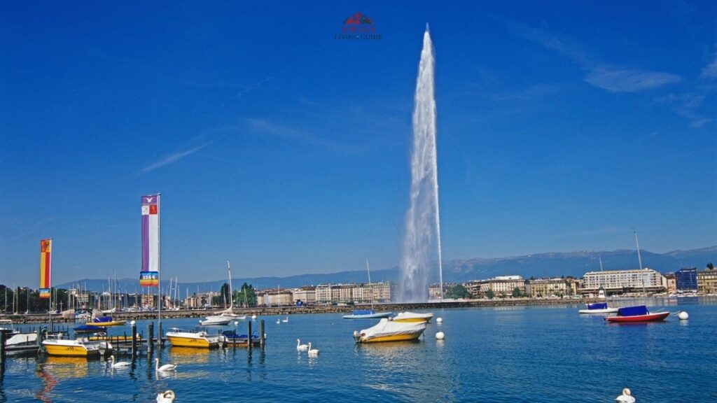 Jet d’Eau fountain rising above Lake Geneva with sailboats and mountains under a clear blue sky